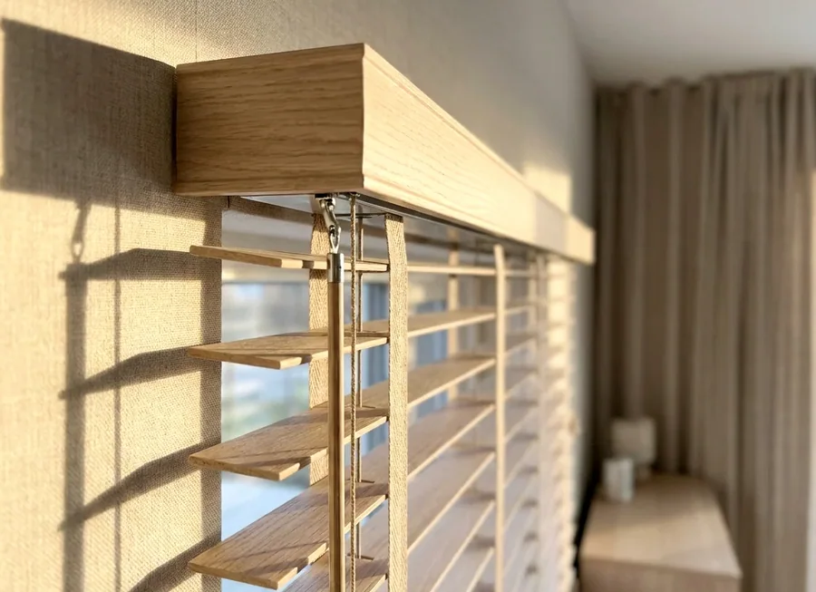 Close-up of a timber venetian blind headrail and tilt mechanism being checked over during a repair in a Blair Atholl home